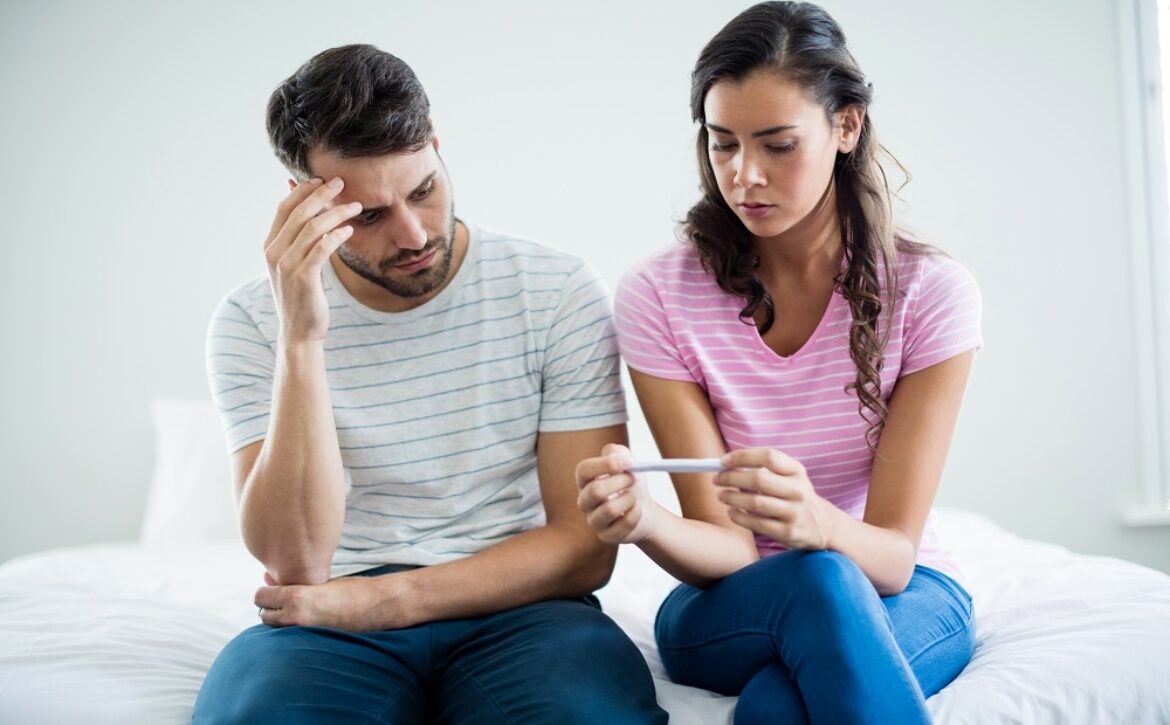 Worried couple finding out results of a pregnancy test in bedroom at home