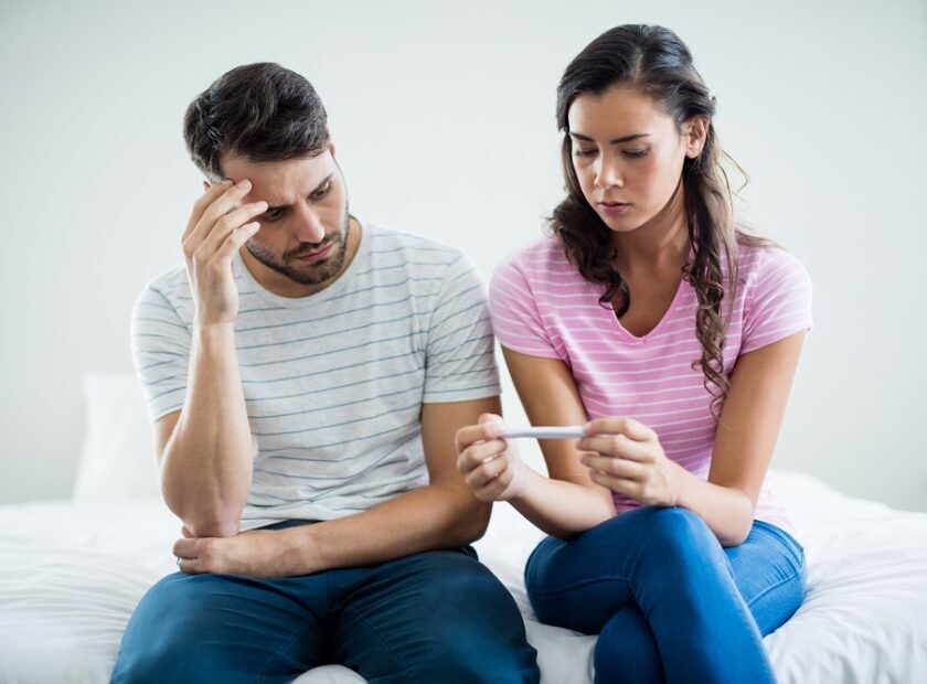 Worried couple finding out results of a pregnancy test in bedroom at home